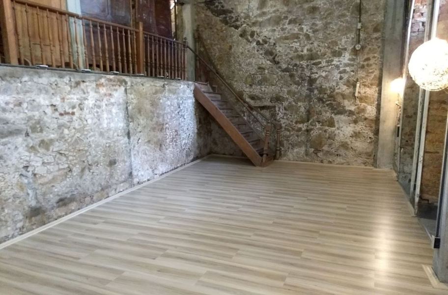 Ambiente de paredes de pedra aparente com escada e mezanino de madeira, cenário para gravação