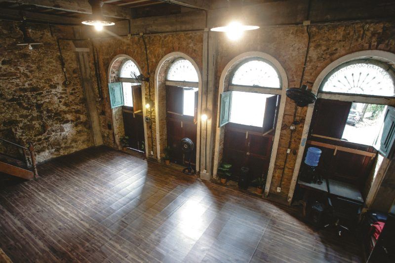 Sala Fluxo vista do mezanino, com quatro portas em arco e piso de madeira